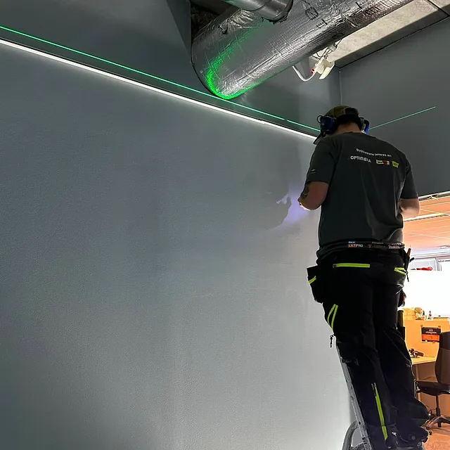 Arbeider på stige med ventilasjonsrør over.