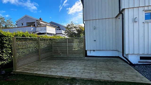 Nybygd treterrasse med levegg ved hvitt hus.