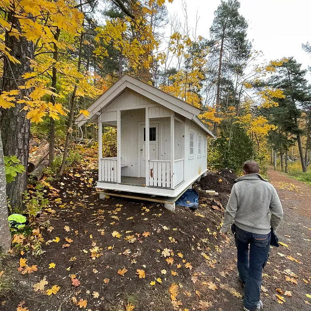 Hytte plassert på bakken, mann går forbi.