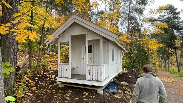 Hytte plassert på bakken, mann går forbi.