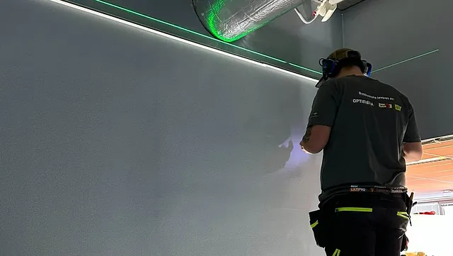 Arbeider på stige med ventilasjonsrør over.